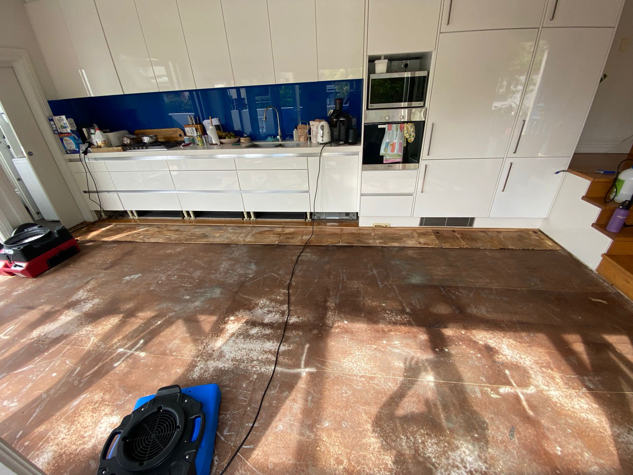Kitchen water damage with floor removed and drying underway