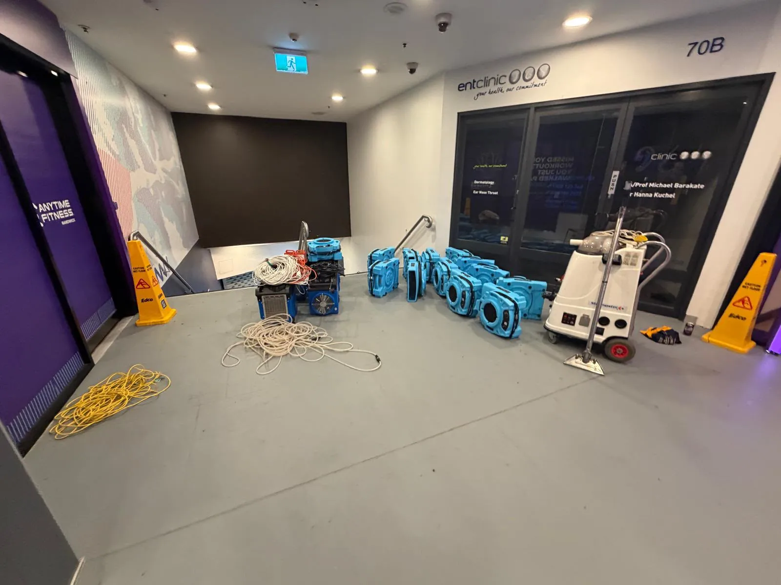 Air movers and restoration equipment set up over a commercial floor
