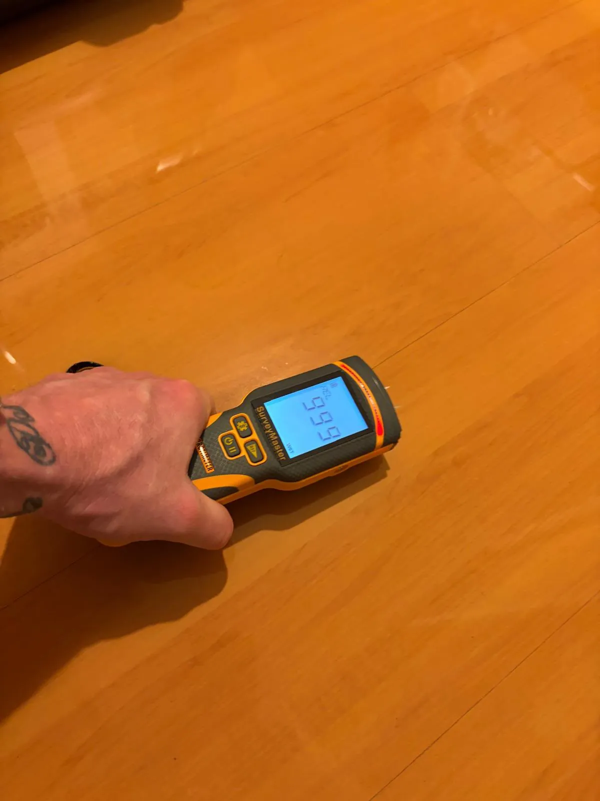 Timber flooring inspection: Close-up meter readings on hardwood flooring.